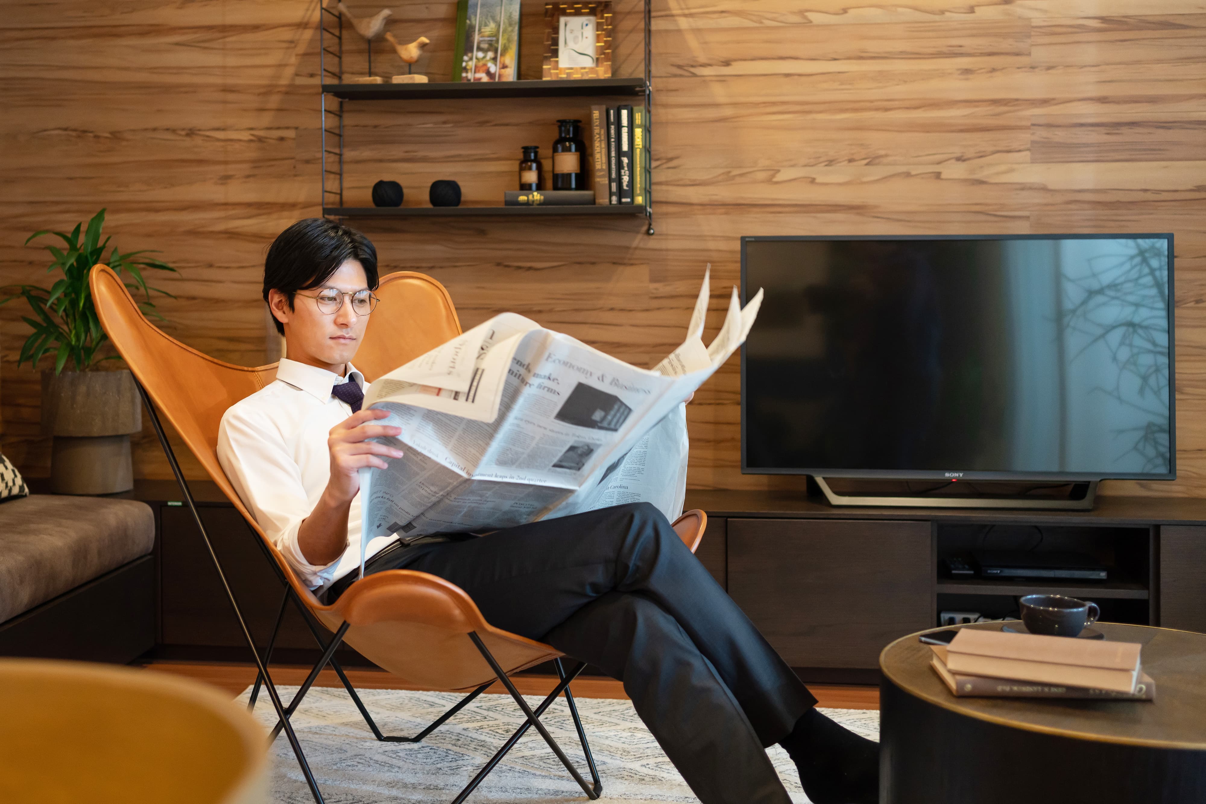 新聞を読む男性とテレビ